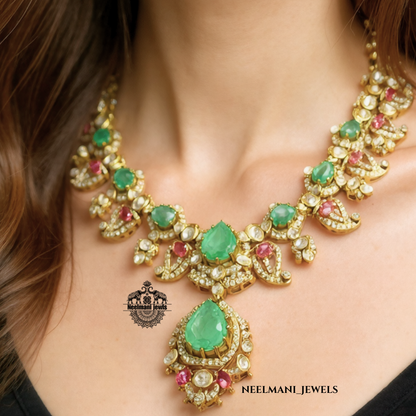 Necklace with green and red gemstones on a model, featuring Neelamani Jewels logo.