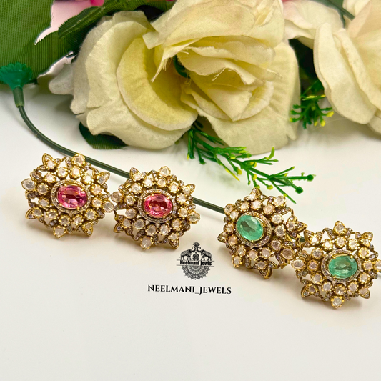 Pair of gold earrings with gemstones on a white background with flowers