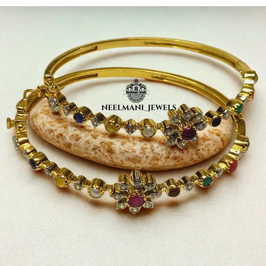 Gold bangles with gemstones on a stone surface, branded as Neelmani Jewels.