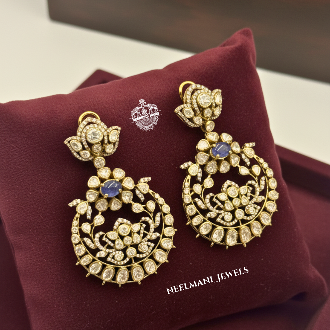 gold earrings with blue stones on a maroon cushion with Neelmani Jewels branding.