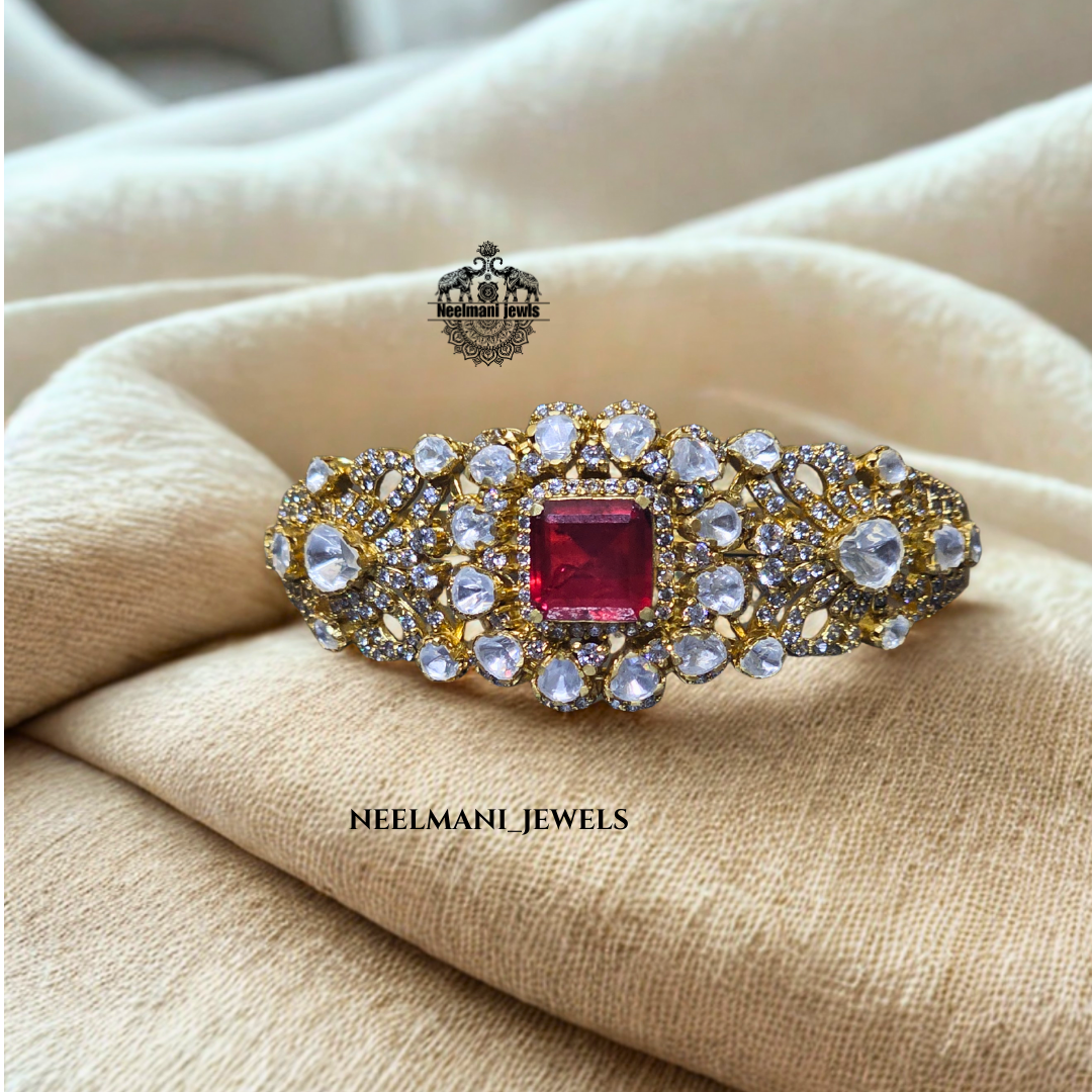 Gold bracelet with a red gemstone , branded 'Neelmani Jewels'.