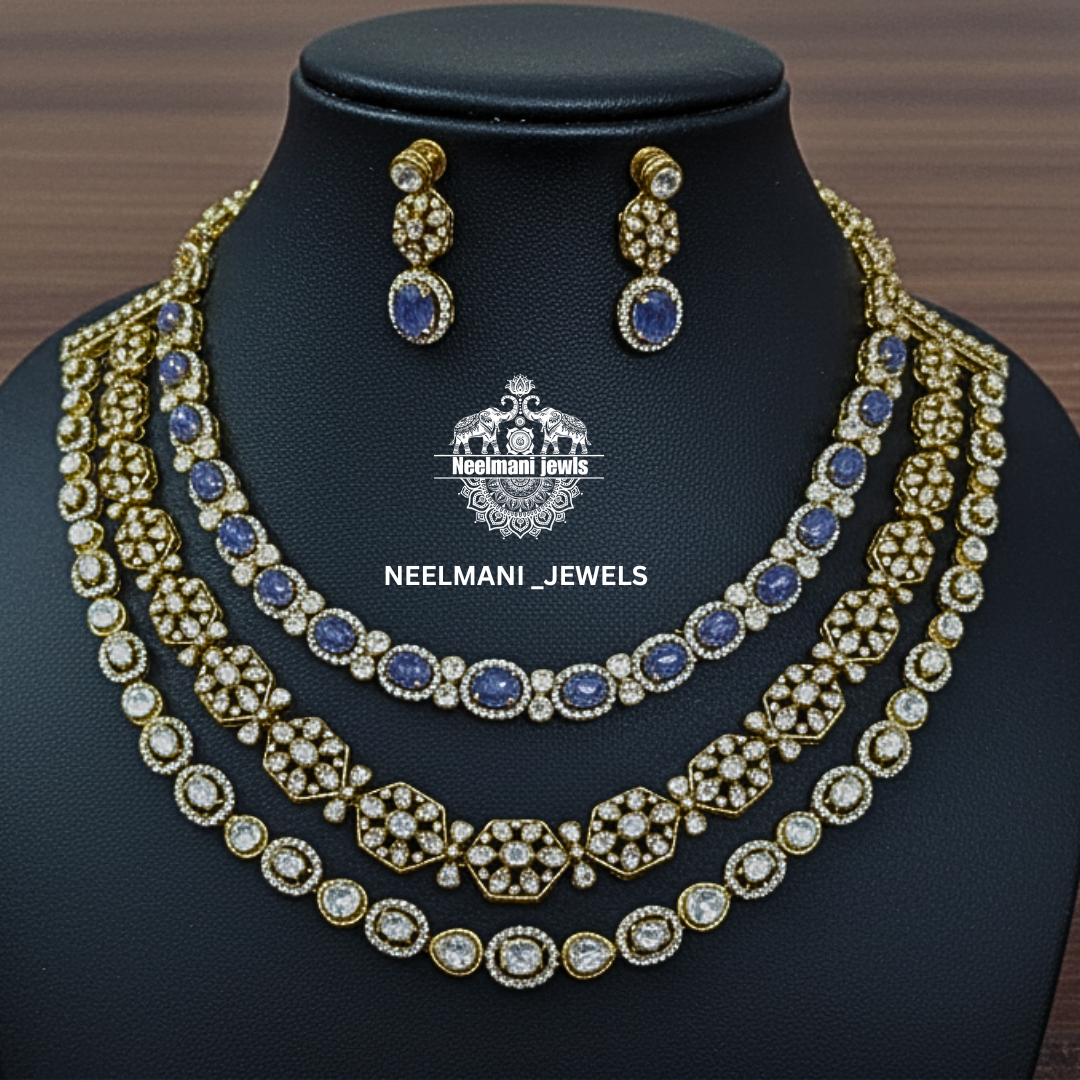 Necklace and earrings set with blue stones on a black stand, branded 'Neelamani Jewels'.